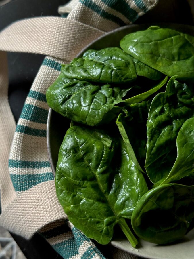 Spinach in a bowl on a table with a striped cloth